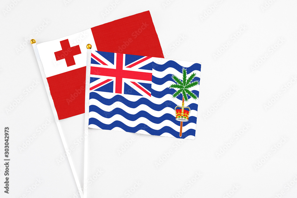 Fototapeta premium British Indian Ocean Territory and Tonga stick flags on white background. High quality fabric, miniature national flag. Peaceful global concept.White floor for copy space.
