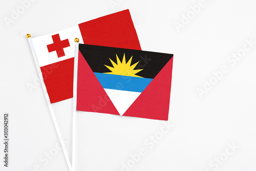 Antigua and Barbuda and Tonga stick flags on white background. High quality fabric, miniature national flag. Peaceful global concept.White floor for copy space.