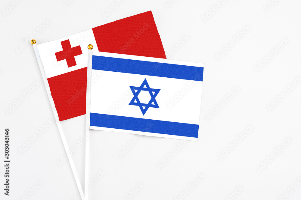 Israel and Tonga stick flags on white background. High quality fabric, miniature national flag. Peaceful global concept.White floor for copy space.