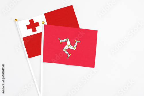 Isle Of Man and Tonga stick flags on white background. High quality fabric, miniature national flag. Peaceful global concept.White floor for copy space.