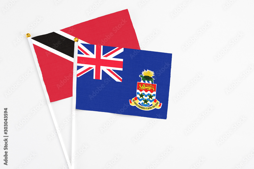 Fototapeta premium Cayman Islands and Trinidad And Tobago stick flags on white background. High quality fabric, miniature national flag. Peaceful global concept.White floor for copy space.