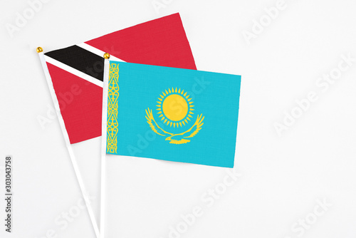 Kazakhstan and Trinidad And Tobago stick flags on white background. High quality fabric, miniature national flag. Peaceful global concept.White floor for copy space.