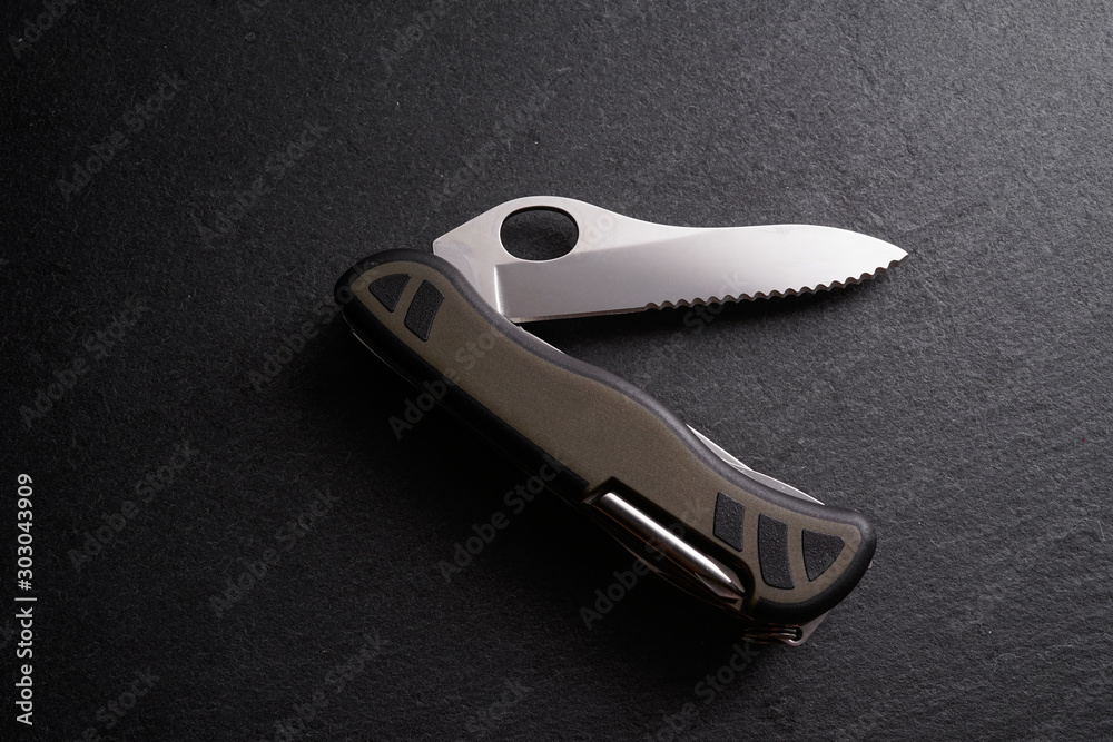 Multipurpose survivor tool knife on dark slate stone background Multipurpose survivor tool knife on dark slate stone background