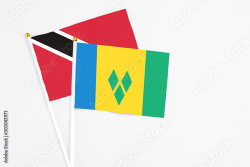 Saint Vincent And The Grenadines and Trinidad And Tobago stick flags on white background. High quality fabric, miniature national flag. Peaceful global concept.White floor for copy space.