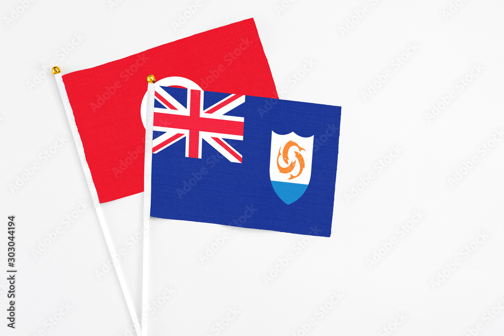 Fototapeta premium Anguilla and Tunisia stick flags on white background. High quality fabric, miniature national flag. Peaceful global concept.White floor for copy space.
