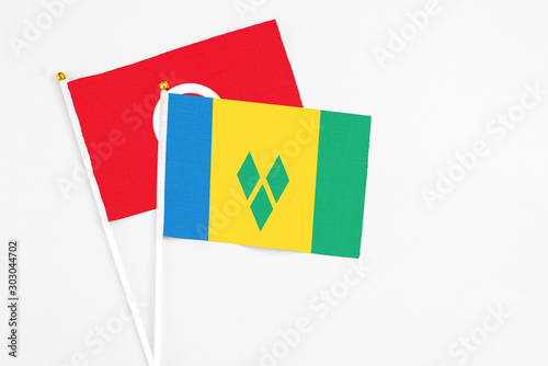 Saint Vincent And The Grenadines and Tunisia stick flags on white background. High quality fabric, miniature national flag. Peaceful global concept.White floor for copy space.