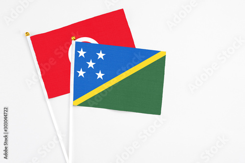 Free Download Solomon Islands and Tunisia stick flags on white background. High quality fabric, miniature national flag. Peaceful global concept.White floor for copy space. - GFXLoad