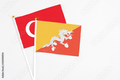Bhutan and Turkey stick flags on white background. High quality fabric, miniature national flag. Peaceful global concept.White floor for copy space.