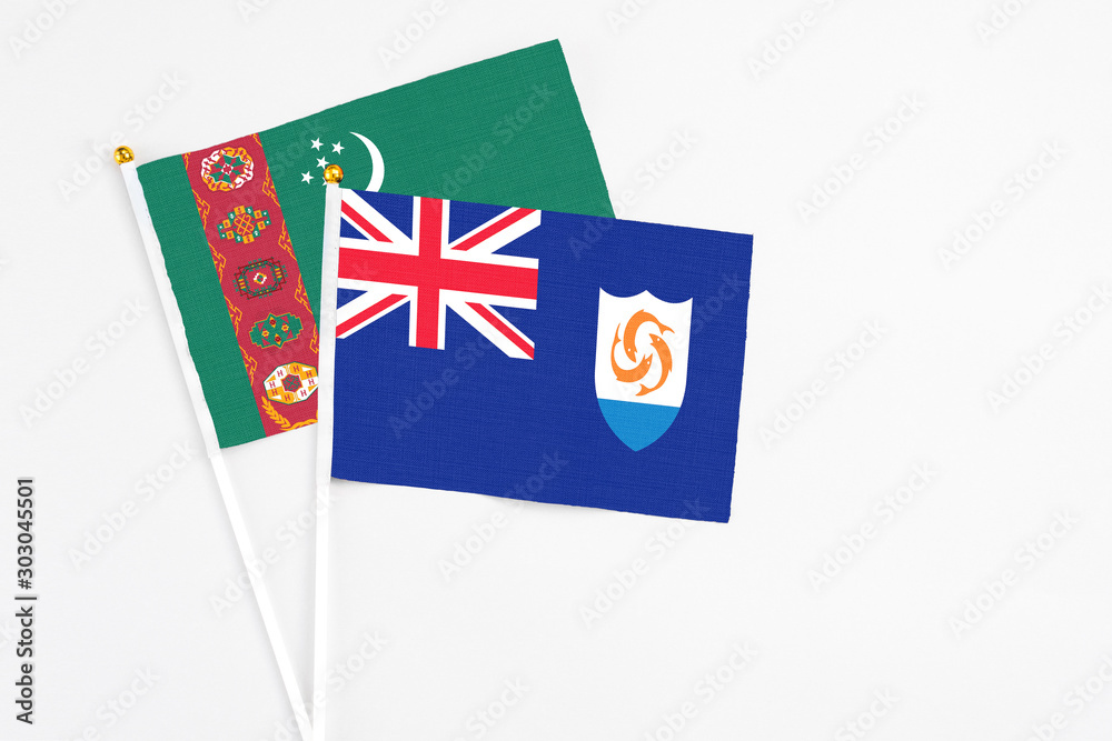 Fototapeta premium Anguilla and Turkmenistan stick flags on white background. High quality fabric, miniature national flag. Peaceful global concept.White floor for copy space.