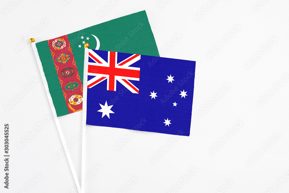 Fototapeta premium Australia and Turkmenistan stick flags on white background. High quality fabric, miniature national flag. Peaceful global concept.White floor for copy space.