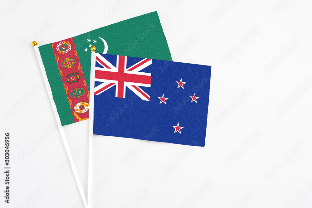 Fototapeta premium New Zealand and Turkmenistan stick flags on white background. High quality fabric, miniature national flag. Peaceful global concept.White floor for copy space.