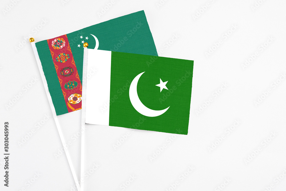 Pakistan and Turkmenistan stick flags on white background. High quality fabric, miniature national flag. Peaceful global concept.White floor for copy space. Pakistan and Turkmenistan stick flags on white background. High quality fabric, miniature national flag. Peaceful global concept.White floor for copy space.