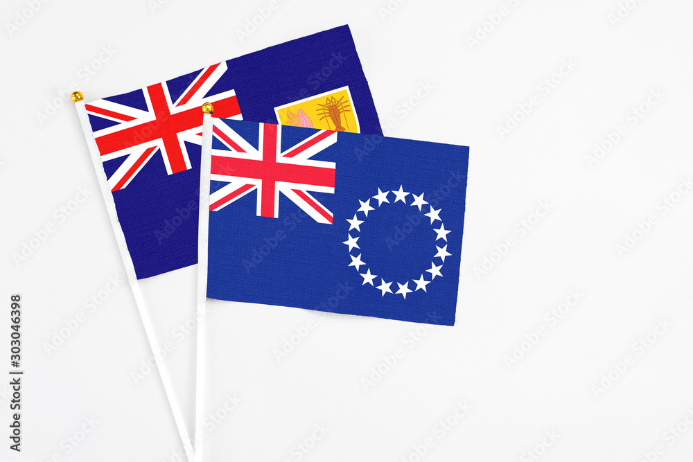 Fototapeta premium Cook Islands and Turks And Caicos Islands stick flags on white background. High quality fabric, miniature national flag. Peaceful global concept.White floor for copy space.