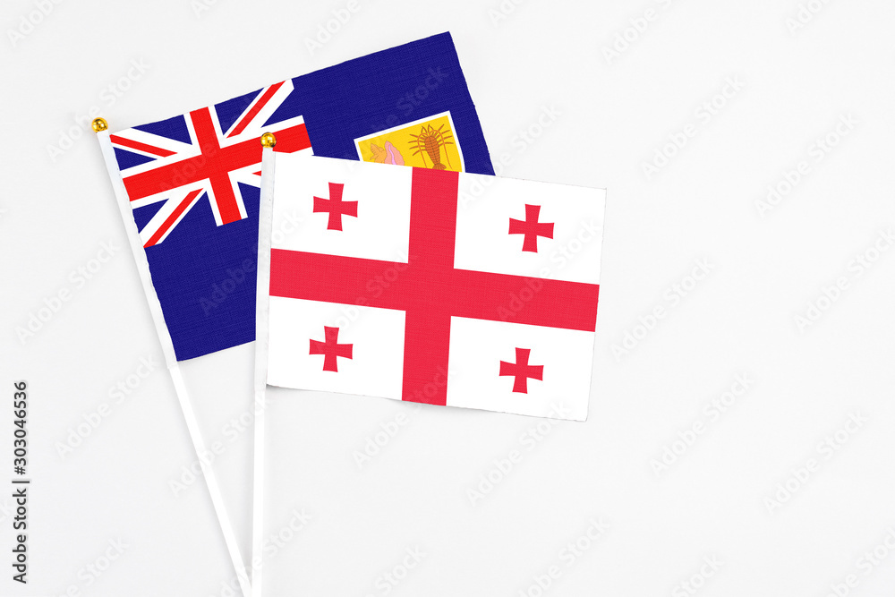 Georgia and Turks And Caicos Islands stick flags on white background. High quality fabric, miniature national flag. Peaceful global concept.White floor for copy space.