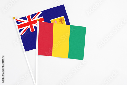 Guinea and Turks And Caicos Islands stick flags on white background. High quality fabric, miniature national flag. Peaceful global concept.White floor for copy space.