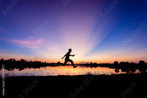 Freedom-young man is jumping at lake with sunset sky