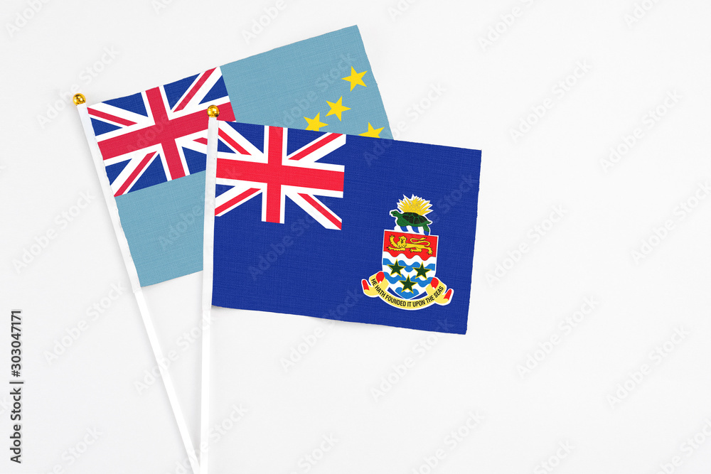 Fototapeta premium Cayman Islands and Tuvalu stick flags on white background. High quality fabric, miniature national flag. Peaceful global concept.White floor for copy space.