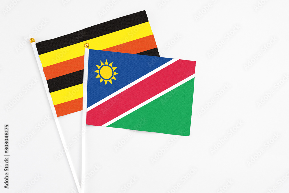 Namibia and Uganda stick flags on white background. High quality fabric, miniature national flag. Peaceful global concept.White floor for copy space. Namibia and Uganda stick flags on white background. High quality fabric, miniature national flag. Peaceful global concept.White floor for copy space.