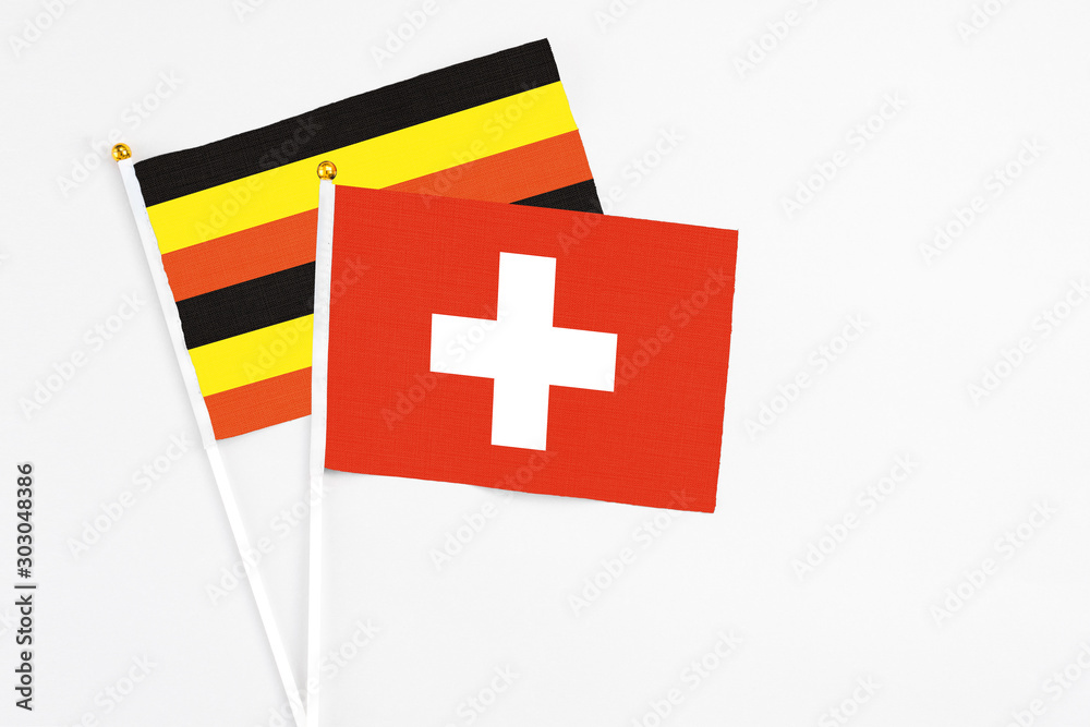 Switzerland and Uganda stick flags on white background. High quality fabric, miniature national flag. Peaceful global concept.White floor for copy space.