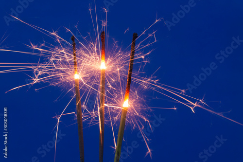Burning sparklers on blue background