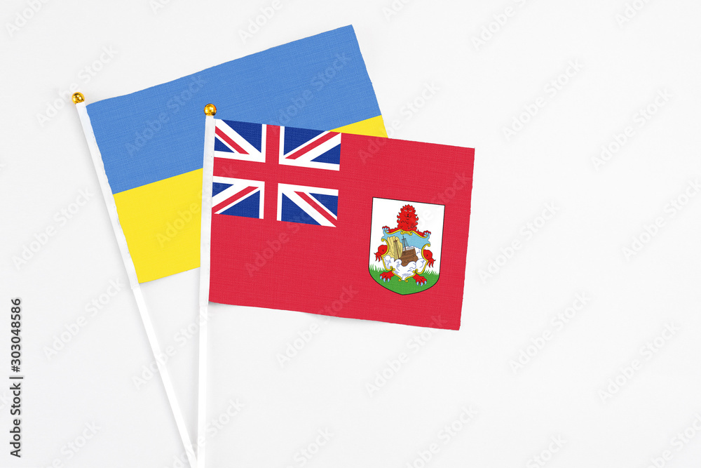 Fototapeta premium Bermuda and Ukraine stick flags on white background. High quality fabric, miniature national flag. Peaceful global concept.White floor for copy space.