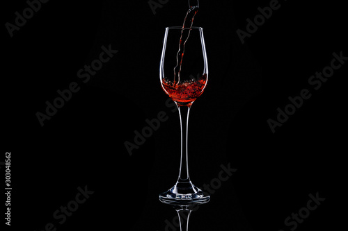 pouring red wine in glass on dark background. Isolated silhouette