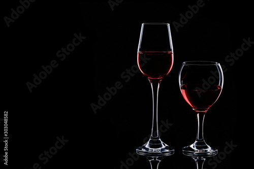 Two glasses silhouette with red wine isolated on black background