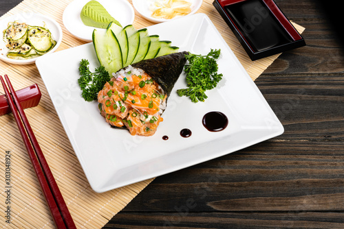 Salmon temaki sushi on white plate in black background. Japanese cuisine. photo