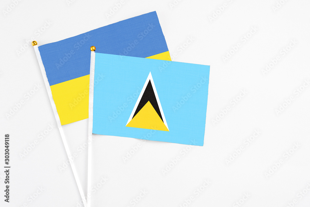 Saint Lucia and Ukraine stick flags on white background. High quality fabric, miniature national flag. Peaceful global concept.White floor for copy space. Saint Lucia and Ukraine stick flags on white background. High quality fabric, miniature national flag. Peaceful global concept.White floor for copy space.