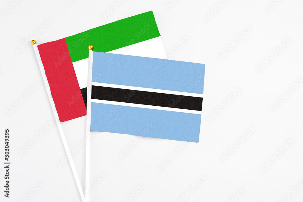 Botswana and United Arab Emirates stick flags on white background. High quality fabric, miniature national flag. Peaceful global concept.White floor for copy space.