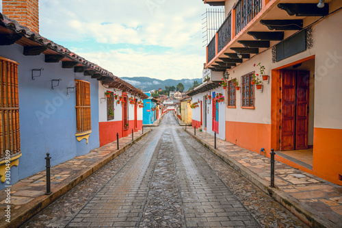 Colorful street of a Mexican town San Cristobal De Las Casas in Chiapas, in the background wooded mountains and a cloudy sky