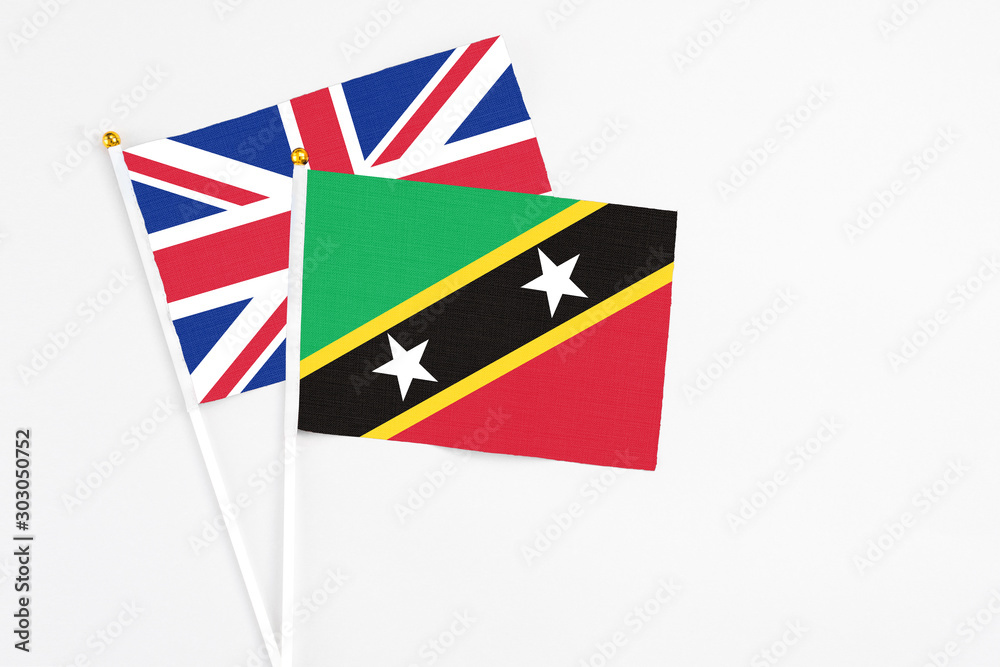 Fototapeta premium Saint Kitts And Nevis and United Kingdom stick flags on white background. High quality fabric, miniature national flag. Peaceful global concept.White floor for copy space.