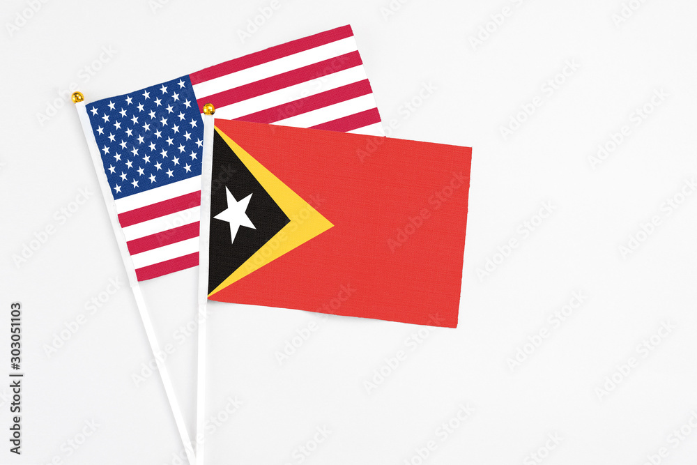East Timor and United States stick flags on white background. High quality fabric, miniature national flag. Peaceful global concept.White floor for copy space.