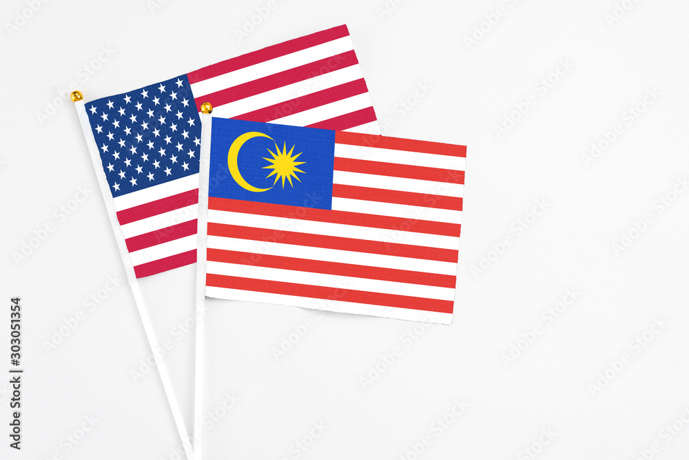 Malaysia and United States stick flags on white background. High quality fabric, miniature national flag. Peaceful global concept.White floor for copy space. Malaysia and United States stick flags on white background. High quality fabric, miniature national flag. Peaceful global concept.White floor for copy space.