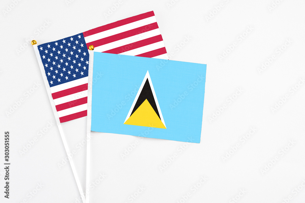 Obraz premium Saint Lucia and United States stick flags on white background. High quality fabric, miniature national flag. Peaceful global concept.White floor for copy space.