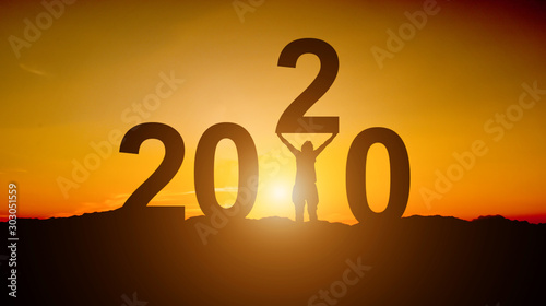 Silhouette of Businessman tries to Lift up number of 2020. Happy new year concept
