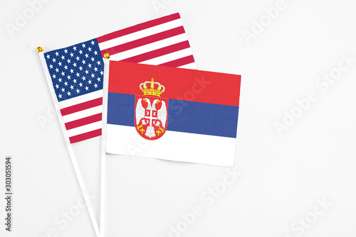 Serbia and United States stick flags on white background. High quality fabric, miniature national flag. Peaceful global concept.White floor for copy space.