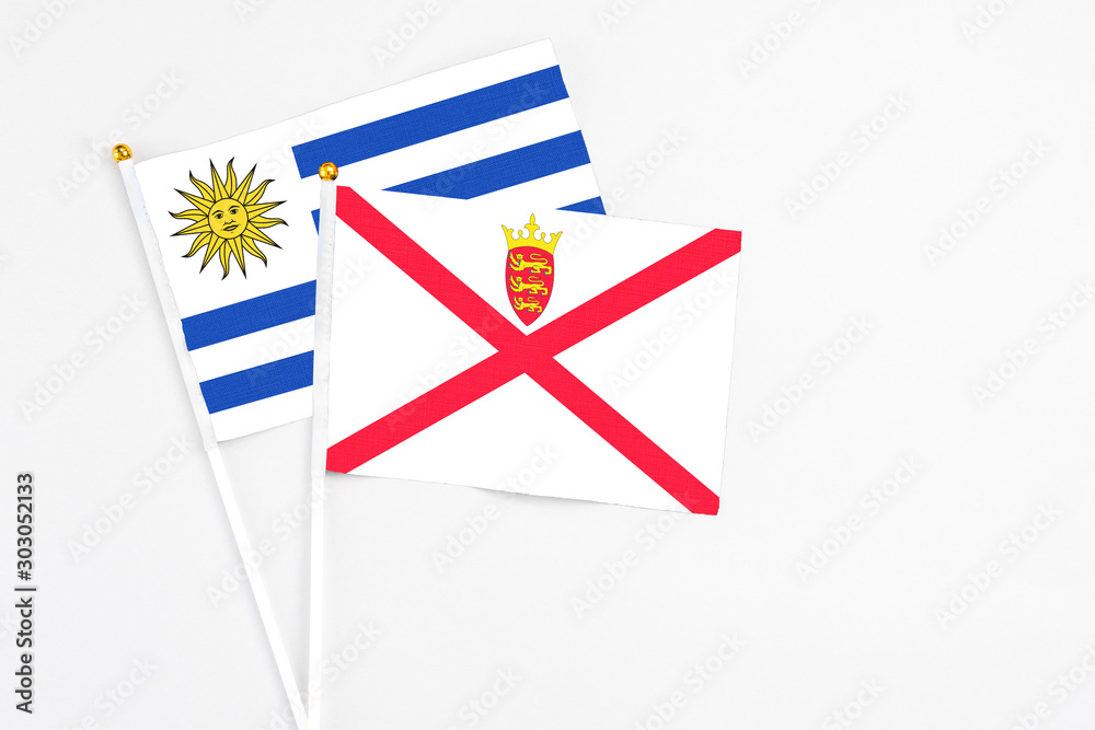 Jersey and Uruguay stick flags on white background. High quality fabric, miniature national flag. Peaceful global concept.White floor for copy space. Jersey and Uruguay stick flags on white background. High quality fabric, miniature national flag. Peaceful global concept.White floor for copy space.