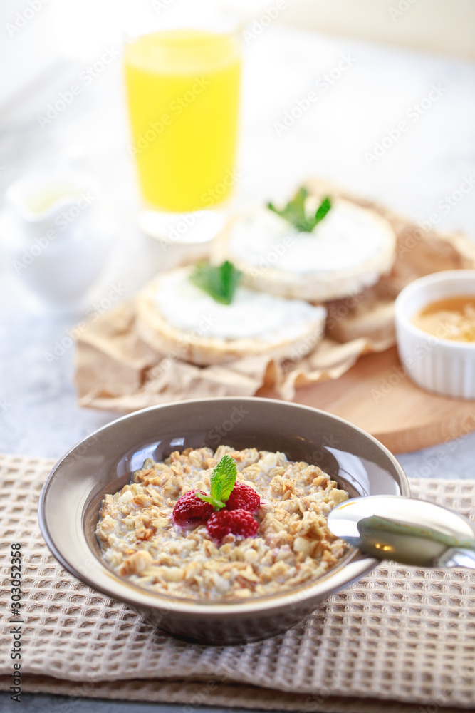 Baked granola with milk and raspberries in a plate, whole grain breads and freshly squeezed juice. A wholesome and dietary breakfast. Delicious muesli.