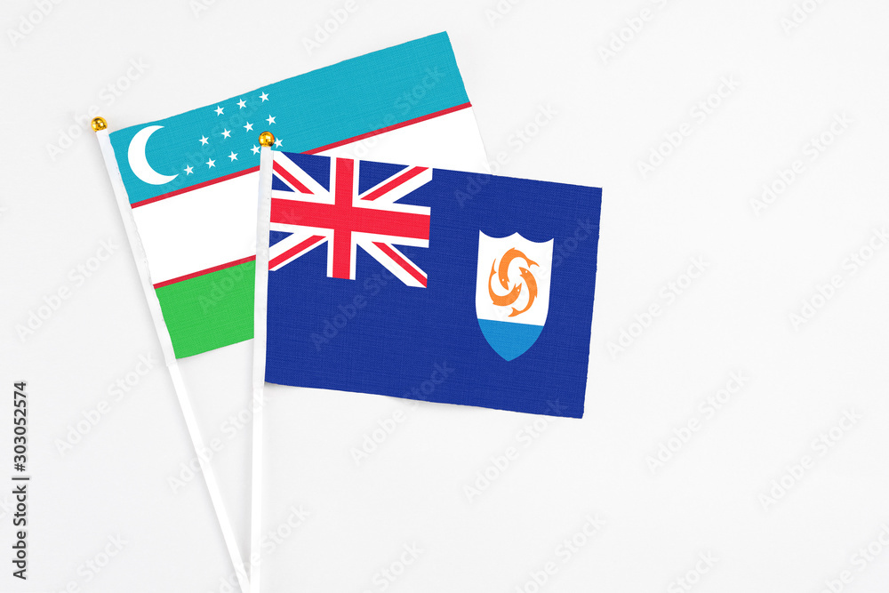 Fototapeta premium Anguilla and Uzbekistan stick flags on white background. High quality fabric, miniature national flag. Peaceful global concept.White floor for copy space.