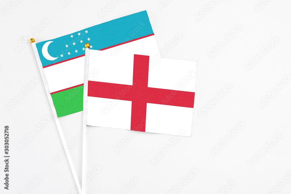 England and Uzbekistan stick flags on white background. High quality fabric, miniature national flag. Peaceful global concept.White floor for copy space.