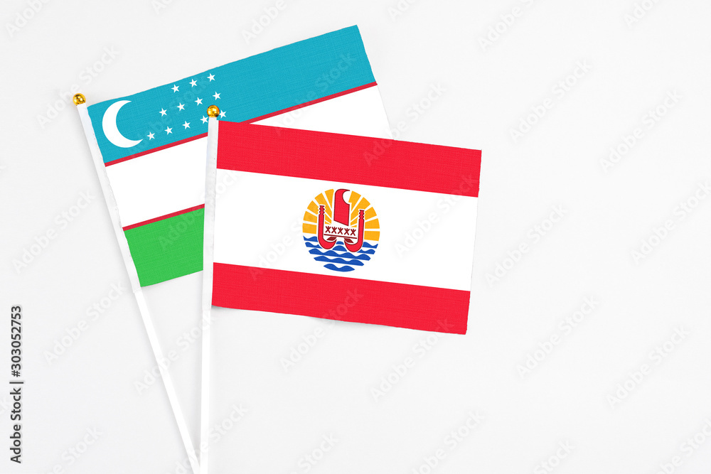 French Polynesia and Uzbekistan stick flags on white background. High quality fabric, miniature national flag. Peaceful global concept.White floor for copy space. French Polynesia and Uzbekistan stick flags on white background. High quality fabric, miniature national flag. Peaceful global concept.White floor for copy space.