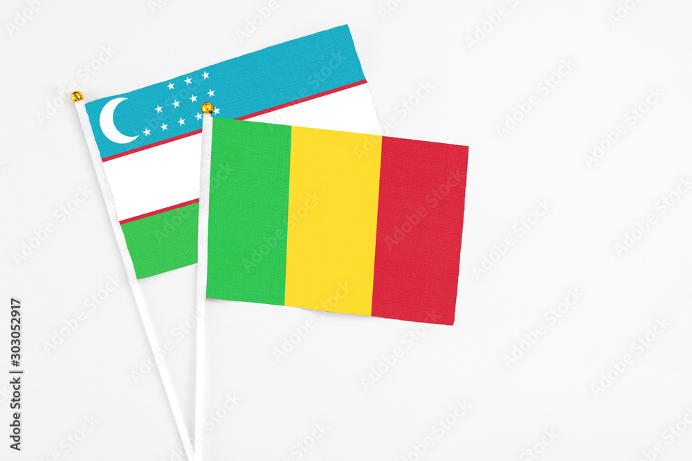 Mali and Uzbekistan stick flags on white background. High quality fabric, miniature national flag. Peaceful global concept.White floor for copy space.
