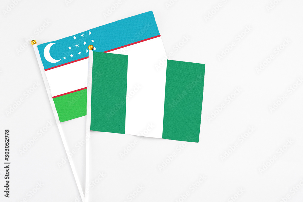 Nigeria and Uzbekistan stick flags on white background. High quality fabric, miniature national flag. Peaceful global concept.White floor for copy space. Nigeria and Uzbekistan stick flags on white background. High quality fabric, miniature national flag. Peaceful global concept.White floor for copy space.