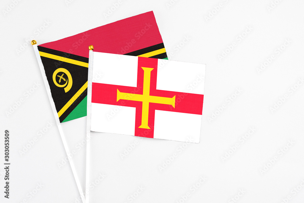 Guernsey and Vanuatu stick flags on white background. High quality fabric, miniature national flag. Peaceful global concept.White floor for copy space.