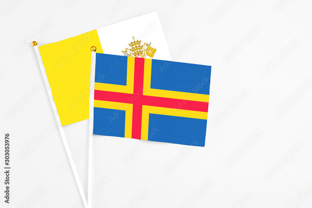Aland Islands and Vatican City stick flags on white background. High quality fabric, miniature national flag. Peaceful global concept.White floor for copy space.