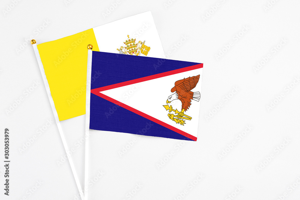 American Samoa and Vatican City stick flags on white background. High quality fabric, miniature national flag. Peaceful global concept.White floor for copy space.