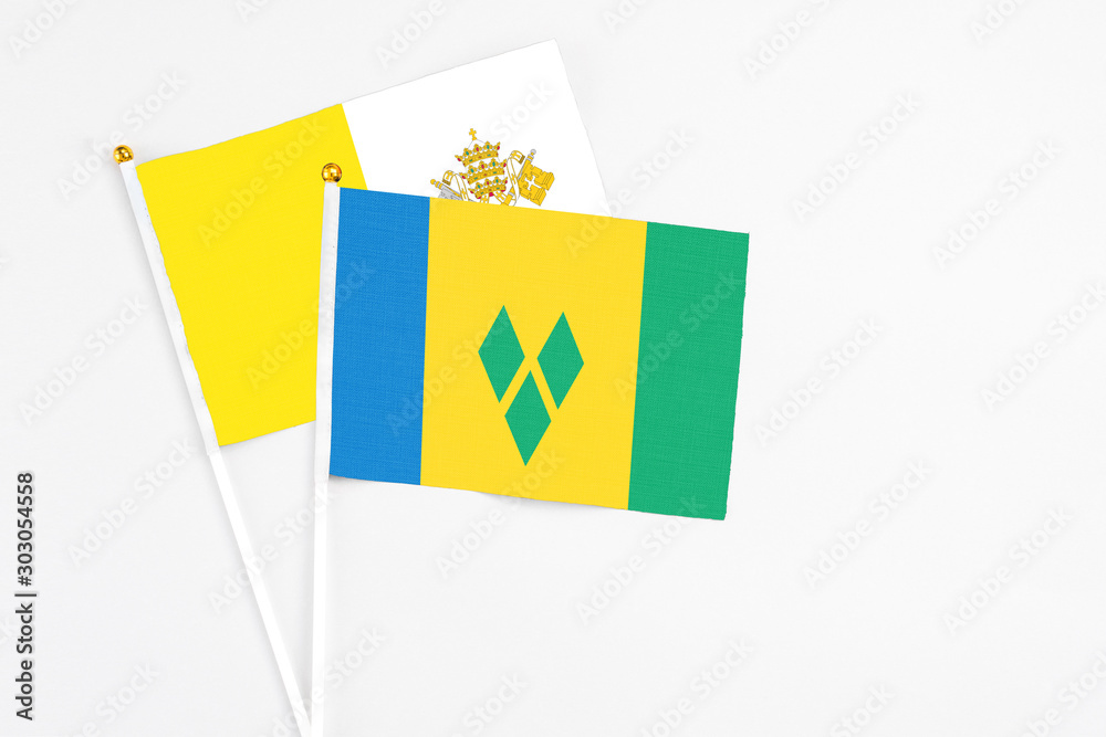 Saint Vincent And The Grenadines and Vatican City stick flags on white background. High quality fabric, miniature national flag. Peaceful global concept.White floor for copy space. Saint Vincent And The Grenadines and Vatican City stick flags on white background. High quality fabric, miniature national flag. Peaceful global concept.White floor for copy space.