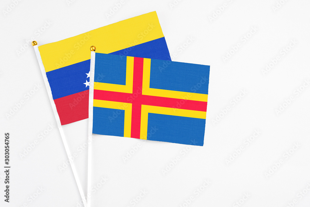 Aland Islands and Venezuela stick flags on white background. High quality fabric, miniature national flag. Peaceful global concept.White floor for copy space.