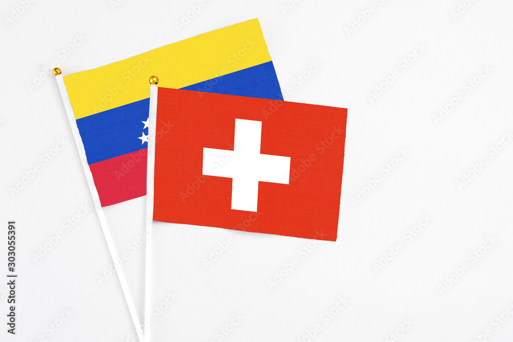 Switzerland and Venezuela stick flags on white background. High quality fabric, miniature national flag. Peaceful global concept.White floor for copy space.